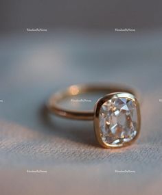 an engagement ring with a cushion cut diamond in the center, sitting on a surface