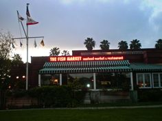 the fish market and seafood restaurant is lit up at dusk with palm trees in the background