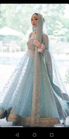 a woman in a blue and gold bridal gown is posing for the camera with her hands on her hips