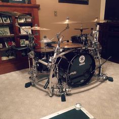 a drum set sitting on top of a carpeted floor next to a book shelf