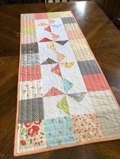 a quilted table runner on top of a wooden table