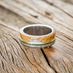 a wedding band that has been made to look like a mountain range is shown on top of a wooden surface