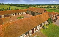 an aerial view of a large building with red roofing and green fields in the background