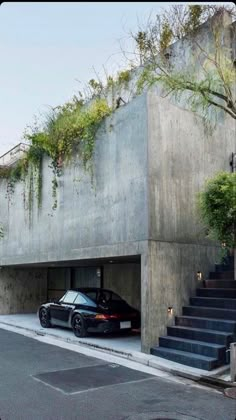 a black car parked in front of a building with plants growing on it's roof