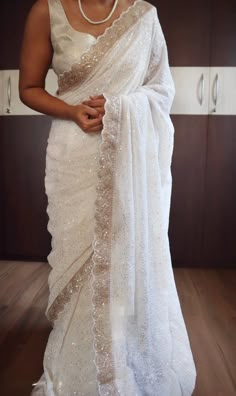 a woman wearing a white sari and pearls