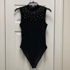 a black leotard with silver sequins hanging on a door