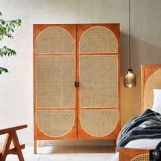 a bedroom with an armoire and bed next to a potted plant on the floor