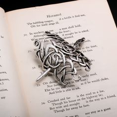 an open book with a silver brooch sitting on top of it's pages