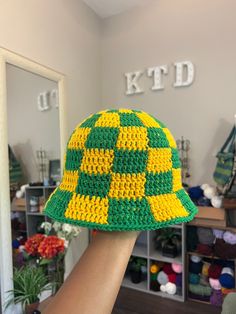 a crocheted green and yellow hat is being held up