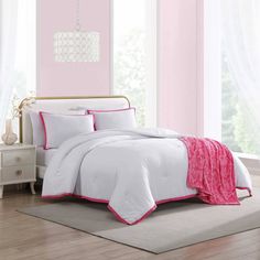 a white bed with pink trim and pillows in a room that is painted light pink