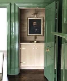 an open door leading to a bathroom with a painting on the wall and wooden floors