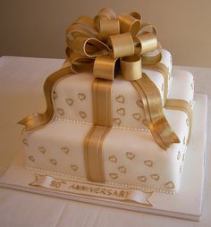 a white cake with gold ribbon and bow on top