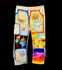 a pair of white pants with colorful pictures on the front and side pockets, all painted in different colors