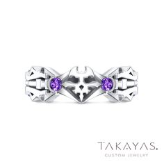 a white gold ring with two purple stones on the center and an intricate design in the middle