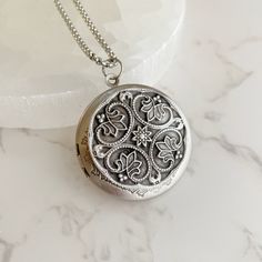 "Now offering custom text engraving.  Visit shop for details. Elevate your style with this stunning and timeless antiqued silver locket. The perfect blend of vintage charm and modern elegance, this piece will complement any outfit, whether dressed up or casual. Crafted from high-quality plated brass, this locket is both lightweight and durable. The 32mm diameter makes it a perfect size for any neckline. The locket opens to reveal a secret place to keep your cherished pictures or messages close to your heart. The locket comes with a stainless steel rolo chain, available in 18\", 20\", 24\" or 30\" length. The hypoallergenic nature of stainless steel makes it an excellent choice for those with sensitive skin. Plus, it will never tarnish or lose its shine, ensuring that this beautiful piece w Antique Silver Engraved Locket Necklace For Memorial, Engraved Antique Silver Locket Necklace For Memorial, Victorian Etched Locket Necklace As Gift, Victorian Etched Locket Necklace For Gift, Victorian Etched Locket Necklace Gift, Vintage Engraved Sterling Silver Locket Necklace, Vintage Sterling Silver Engraved Locket Necklace, Vintage Necklace With Engraving Option For Keepsake, Antique Silver Sterling Silver Vintage Locket Necklace