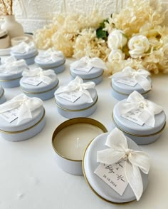 wedding favors are arranged on a table with flowers in the backgrouf and candles