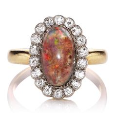 Vintage Opal and Diamond Cocktail Ring The Livingston ring is an authentic vintage opal and diamond ring from the Edwardian Era circa 1900. The ring centers a GIA Certified beautiful Brown and White hued opal surrounded by a halo of 18 old cut diamonds. The stones are set in platinum and 18kt yellow gold setting. The r Antique Opal Wedding Rings, Vintage Diamond Opal Ring, Vintage Diamond Opal Ring For Anniversary, Vintage Opal Ring With Oval Cabochon, Vintage Diamond Opal Wedding Ring, Victorian Opal Oval Cabochon Ring For Wedding, Heirloom Oval Opal Ring With Halo Setting, Victorian Opal Ring For Wedding, Heirloom Opal Ring With Rose Cut Diamonds