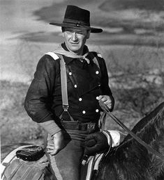 black and white photograph of a man in uniform riding a horse with a hat on