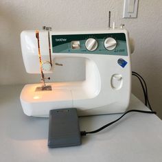 a white sewing machine sitting on top of a table next to a small light switch