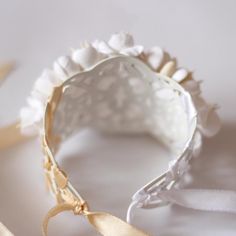 a white headband with gold ribbon and flowers