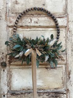 a wreath is hanging on a door with a ribbon tied around it and attached to the front door