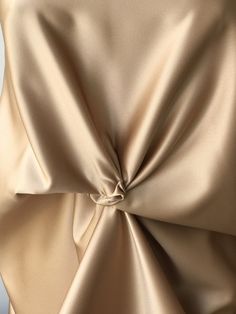 the back of a woman's tan dress with a knot at the waistline