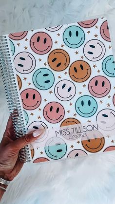 a person holding a notebook with smiley faces on it