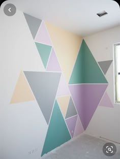 an empty room with a wall painted in pastel colors and triangles on the wall