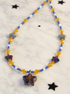 16 inch beaded star necklace arrives in ready to gift packaging. Bright yellow, orange, blue and white seed beads interspersed with small electroplated stars and a Purple carnival glass star come together for a  whimsical choker necklace. Fairy core aesthetic is perfect for a young girl or teen's birthday or for anyone who loves sparkly celestial themed jewelry. Clasp and fittings are sterling silver. Purple Star Necklace, Fairy Core Jewelry, Fairy Core Aesthetic, Necklace Fairy, Star Choker, Beaded Star, Seed Bead Choker, Accessory Inspo, Festival Necklace