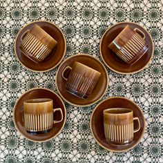 four brown cups and saucers on a table