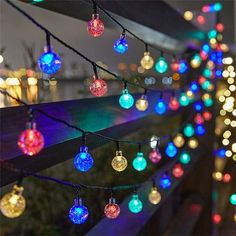 multicolored christmas lights are hanging on a fence