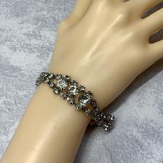 A simple clear rhinestone bracelet. Has a silver tone metal finish with two strands of rhinestones. Larger triple rhinestone center. It fastens with a hinged claps closure. In good used vintage condition. Rhinestones are still pretty bright with minor darkening as is expected from age. See pictures for more details. Perfect for a special even. Rhinestones are prong set so its more durable. Size 7 by 5/8 inches Cup Chain Bracelet, Pageant Jewelry, Rhinestone Cups, Bridal Bracelet, Statement Bracelet, Rhinestone Bracelet, Crystal Gifts, The 1960s, Vintage Rhinestone