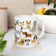 a coffee mug with dogs on it sitting next to some lemons and other fruit