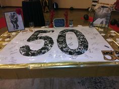 a 50th birthday cake with the number 50 on it and some pictures behind it that is covered in gold foil