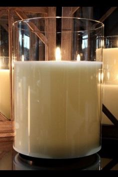 a candle that is sitting in front of some glass containers with candles inside it and on top of the table