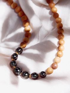 Nestled between natural sandalwood beads sit seven lustrous Tahitian black pearls to give this handmade beaded necklace an enlightened energy from aina (land) to kai (sea). This stunning Tahitian pearl necklace elegantly exemplifies mindful island living. Wear this beaded necklace alone or layered for a classically elegant statement.✦ DETAILS ✦✧ Name: Moana (moh-AH-nah )- from the ocean.✧ Adjustable Length from: 16"-18".✧ 7 Genuine Tahitian Pearls 8-10mm AA-AAA quality; tone and shape varies.✧ 8 Hawaii Necklace, Hawaii Jewelry, Tahitian Pearl Necklace, Handmade Beaded Necklace, Simple Hoop Earrings, Necklace Wood, Tahitian Black Pearls, Black Pearls, Wood Bead Necklace