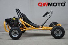 a yellow go kart is parked in front of a wall with the words qw moto written on it