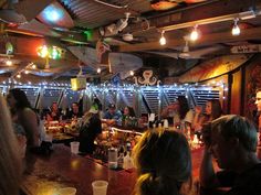 a group of people sitting at a bar in a room with lights on the ceiling