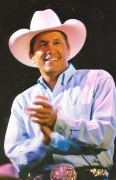 a man wearing a white cowboy hat and holding his hands together