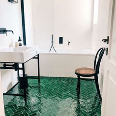 a bathroom with green flooring and a chair in the corner next to the bathtub