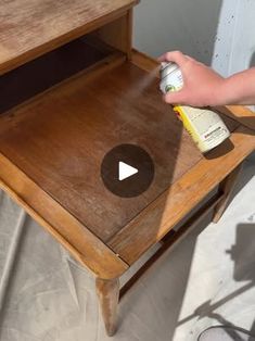 someone using a spray bottle to clean a wooden table