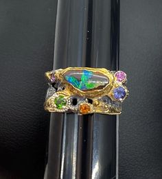 Australian Boulder Opal Gemstone Ring with gold accents size 5 Materials: Silver 925, Australian Opal, Amethyst, Citrine, Iolite, Chrome Diopside  Face of the ring: Height-10mm,Width-10mm(stone), Band-7mm Please note: Colors may vary slightly due to monitor display settings. Items in the photograph are not actual size. Closeup photos are taken. Please read the measurements. PLEASE READ SHOP ANNOUNCEMENT FOR RETURNS AND EXCHANGES THANK YOU FOR LOOKING and SUPPORTING HANDMADE JEWELRY CARE: Please avoid contact with moisture for all jewelry. Apply lotions, sprays and perfumes before putting on jewelry. Take off jewelry before exercise and bed. Keeping your jewelry as dry as possible will help prolong the nature of its color and shine. Store your jewelry when dry only. To clean jewelry, gently Luxury Gold Multi-stone Opal Ring, Collectible Gold Opal Ring With Gemstone, Gold Gemstones Ring With Gemstone Accents, Collectible Gold Opal Gemstone Ring, Unique Multi-stone Opal Ring In Gold, Gold Oval Fusion Gemstones, Oval Gold Fusion Gemstones, Unique Gold Opal Ring With Multi-stone, Gold Multi-stone Gemstones