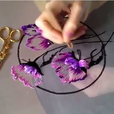 a pair of scissors and some purple flowers on a black wire with gold plating