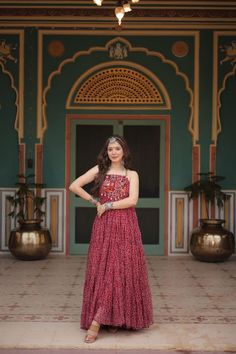 a woman standing in front of a doorway wearing a red dress