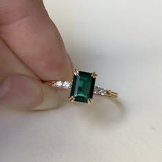 someone is holding an emerald and diamond ring