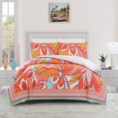 a bed with an orange and blue comforter in a bedroom next to a window