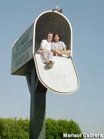 two people sitting on top of a sign with trees in the background