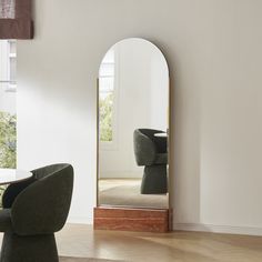 a mirror sitting on top of a wooden floor next to a chair and ottoman in a room