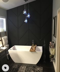 a bathroom with a bathtub, rug and lights hanging from the ceiling above it