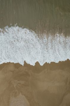 an aerial view of the ocean waves and sand